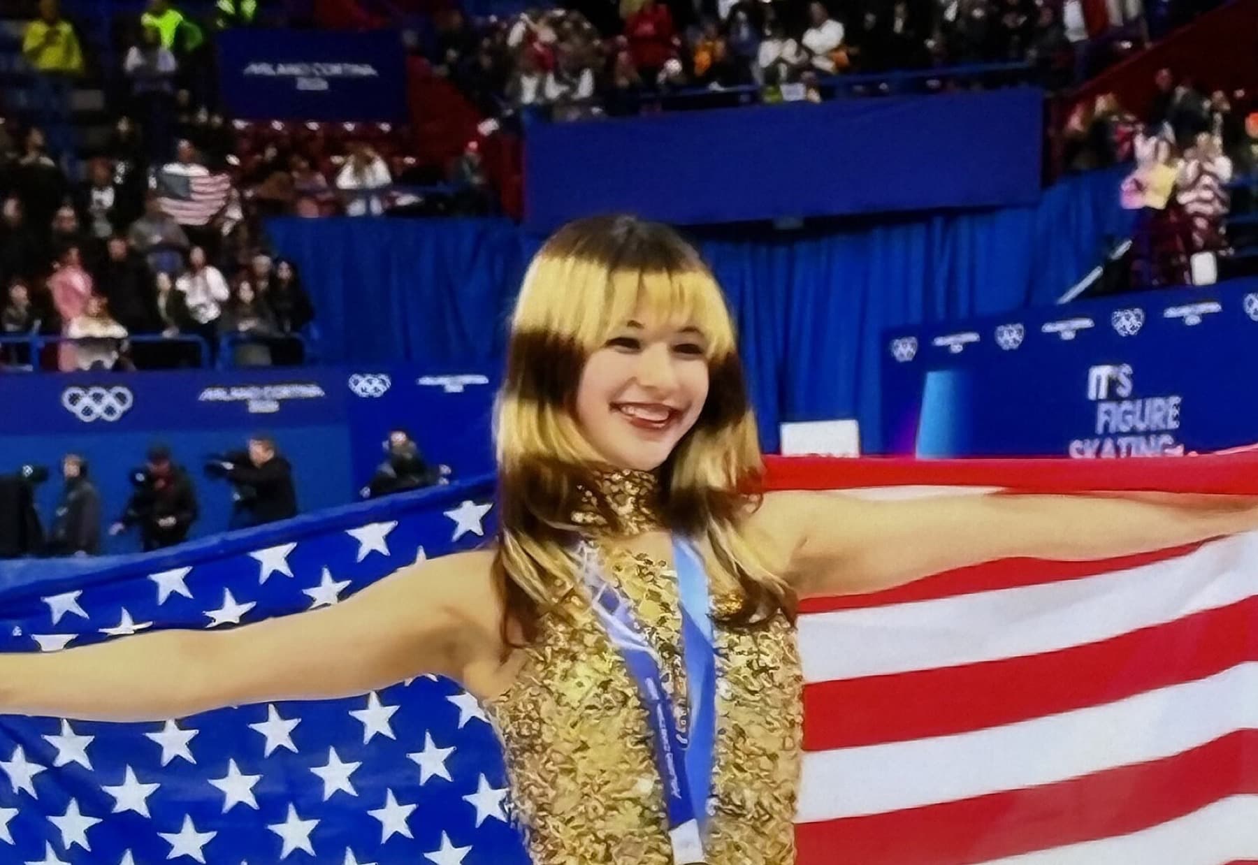 Alysa Liu with Olympic gold and the U.S. flag after the women’s figure skating final at Milano Cortina 2026 — the first American woman to win the title since 2002.