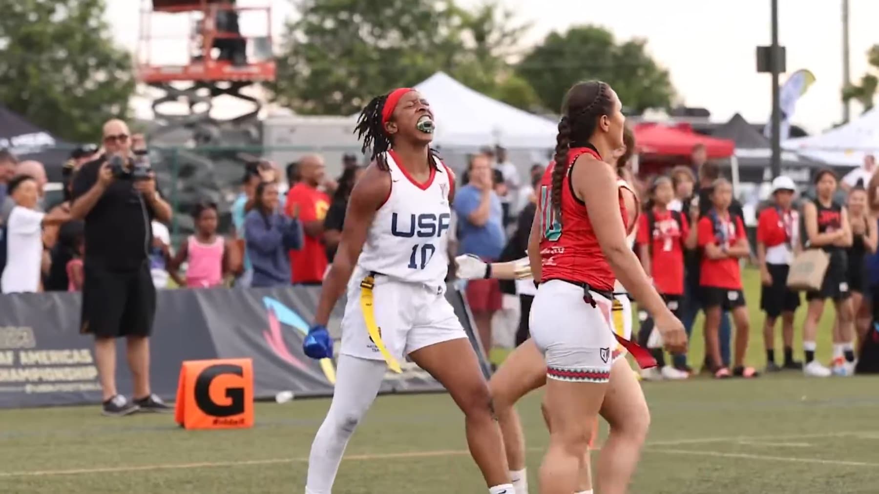 A U.S. women’s national team player celebrates at the 2023 IFAF Americas Championship. The yellow flags at her waist are the same non-tackle format Los Angeles will use in 2028.