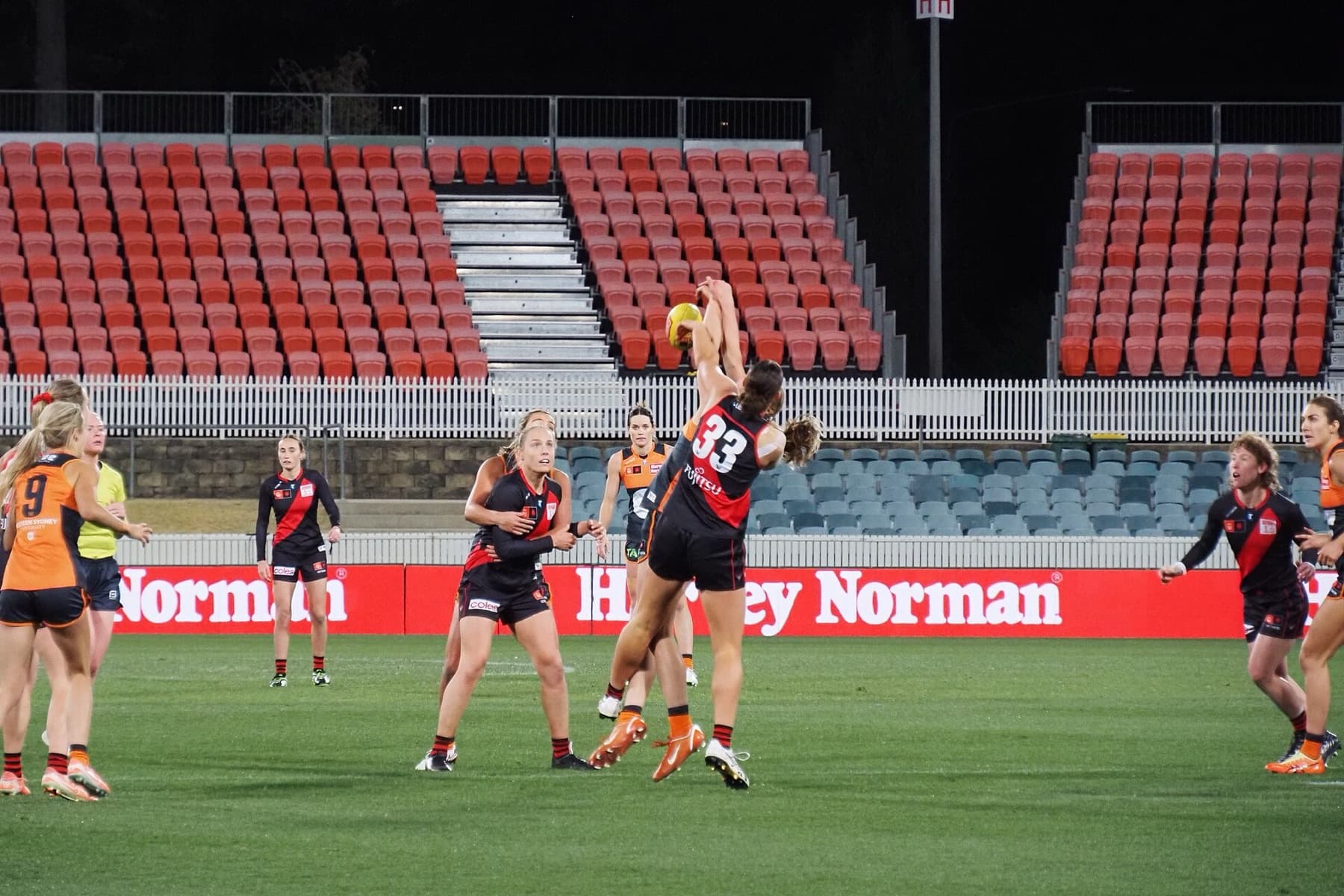 Greater Western Sydney Giants AFLW players contest the ball against Essendon in Canberra on August 16, 2025 — the orange-and-charcoal Giants identity that Super Netball’s Western Sydney franchise has shared since 2017 and will leave behind under new ownership.